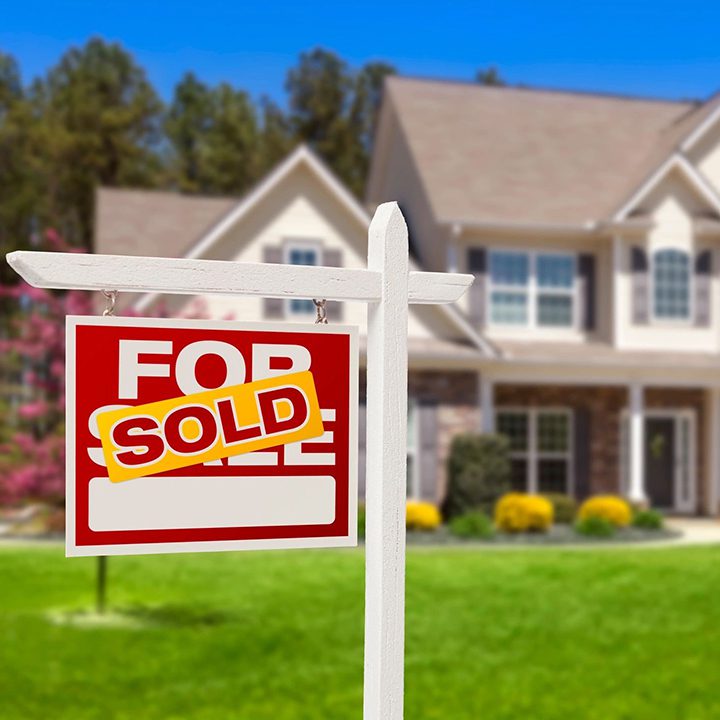 A red sold sign sitting in front of a house.