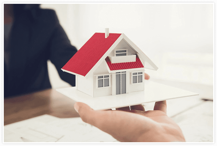 A person holding a small model house in their hand.