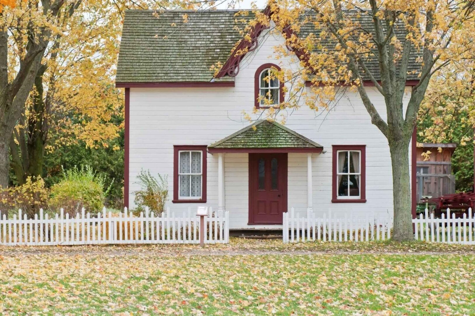 A white house with red trim and a picket fence.